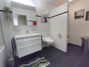 Ein modernes Badezimmer mit einem weißen Waschtisch, einer Toilette und einer Duschkabine.