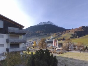 Ein Wohngebiet mit einem Berg im Hintergrund, ein Gebäude mit Balkon und einem klaren Himmel.
