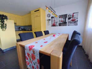 Ein Essbereich mit einem Holztisch, blauen Stühlen und einer Tischdecke mit Blumenmuster.