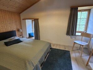 Et soveværelse med seng, stol, vindue og dør.