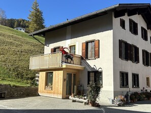 Ein zweistöckiges Gebäude mit Balkon, Holzhörnern und einer Steinwand.