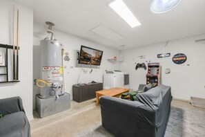 Ein Wohnzimmer mit Sofa, Couchtisch, Fernseher, Warmwasserbereiter und einer Spielkonsole.