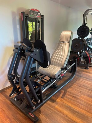 Una palestra con attrezzature per esercizi, tra cui una macchina per leg press e pesi impilati.