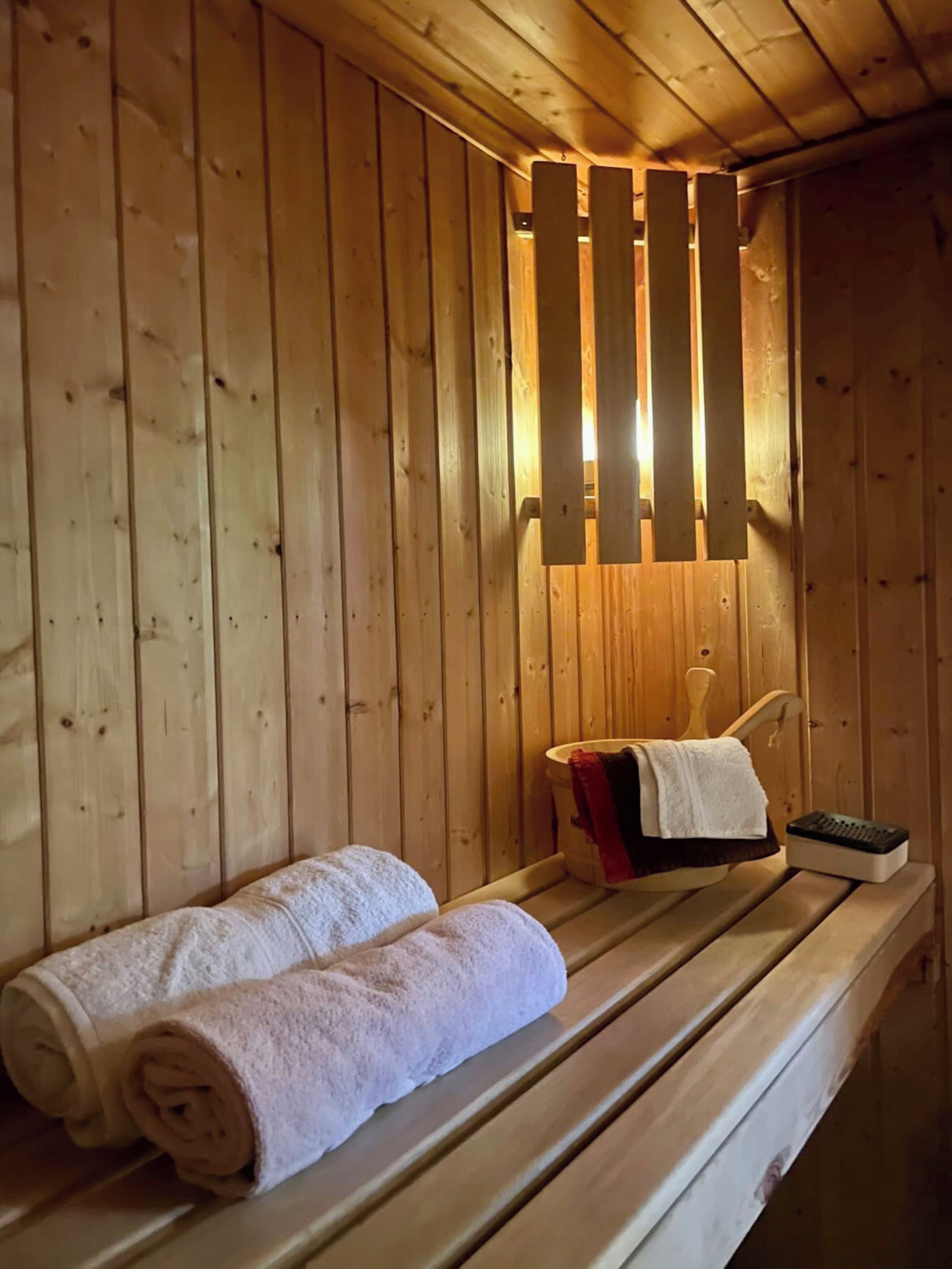 A wooden sauna room with benches and towels.