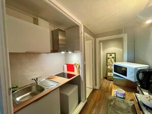 A compact kitchen with a sink, a microwave, and a small refrigerator. - Charming 1-bedroom house with AC in terrific Les Eyzies (les eyzies)