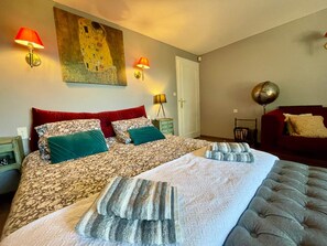 Una camera d'albergo con un letto grande, due abat-jour, un divano rosso, un mappamondo e un quadro appeso al muro.