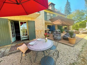 A patio with a round table, chairs, and a red umbrella. - Charming 1-bedroom house with AC in terrific Les Eyzies (les eyzies)