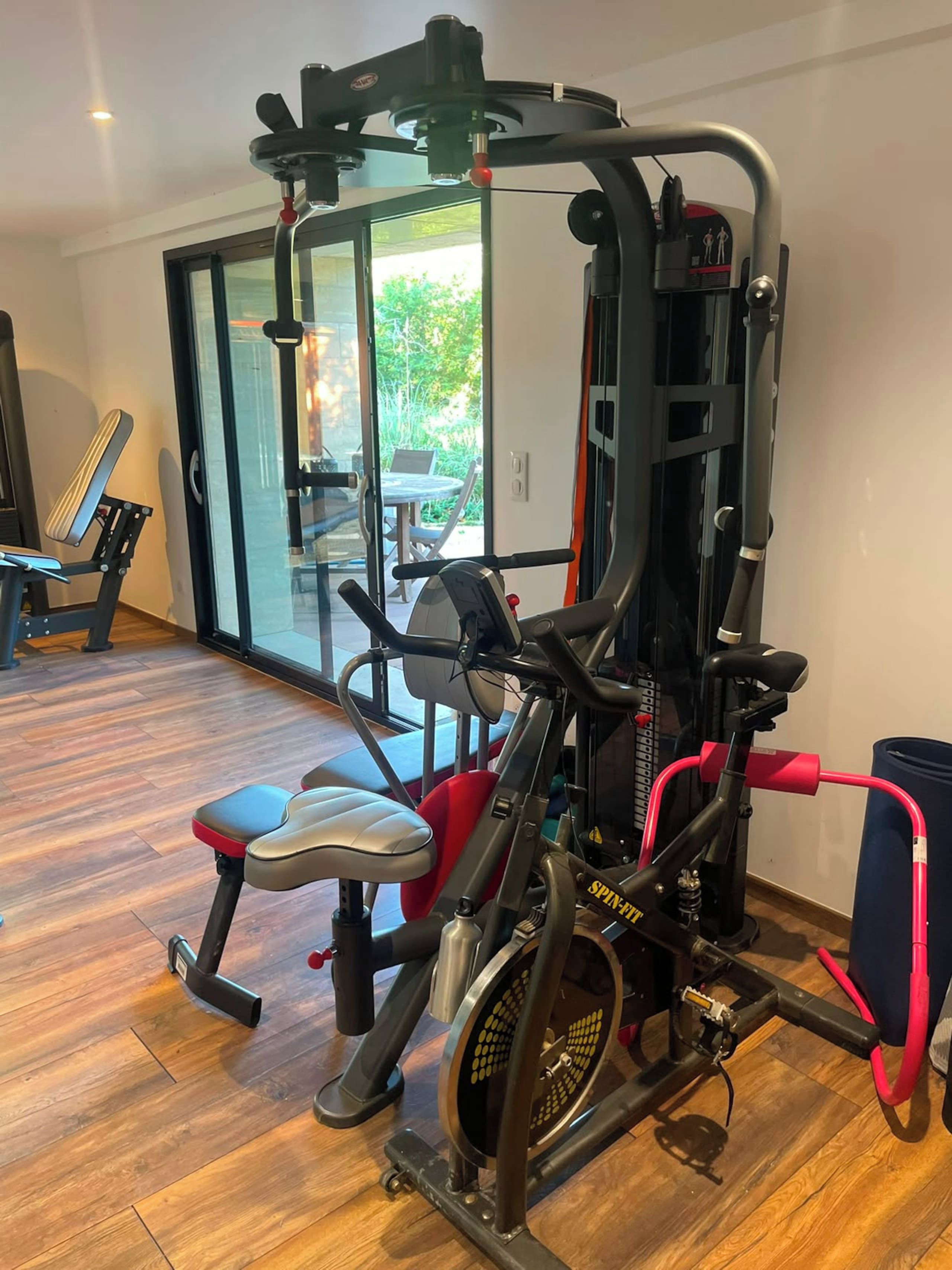 Ein Heimfitnessraum mit Ergometer, einer Bank und einem Krafttrainer.