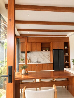 Eine moderne Küche mit Holzschränken, einer Marmorfliesenspiegel und einem schwarzen Kühlschrank.