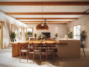 A modern dining area with a wooden table and chairs, a central island, and a ceiling fan. - Ori Villa 5 BR Hoi An Beach 5 min - pool (Đà Nẵng)