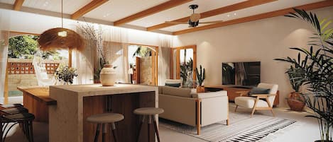 Una cocina moderna con una isla central, taburetes de bar, una zona de comedor con sofá y una sala de estar con televisor.