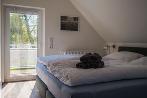 Quarto com cama, radiador, janela com vista e luminária na parede.
