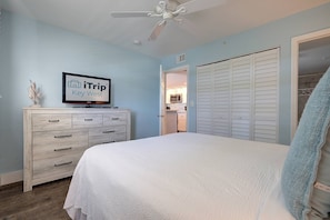 Ein Schlafzimmer mit Bett, Schminktisch, Deckenventilator und einem Fernseher, der 'iTrip Key West' anzeigt.