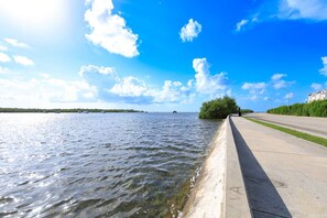 A waterfront view with a concrete walkway, calm water, and distant boats. - Saint Barts | Key West Condo, Pool, Hot Tub & Gym (Key West)