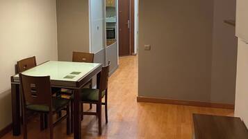 Un comedor con mesa y sillas, una cocina al fondo y un pasillo que conduce a otra habitación.