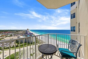 A balcony with a view of the beach and ocean, a round table, and two chairs. - Steps to the Sand! Gulf Front Studio at Boardwalk Resort – Pool, Hot Tubs, Tiki Bar & More! (Panama City Beach)