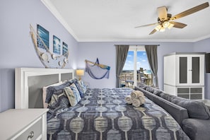 A bedroom with a bed, a sofa, a ceiling fan, and a view of the city. - Steps to the Sand! Gulf Front Studio at Boardwalk Resort – Pool, Hot Tubs, Tiki Bar & More! (Panama City Beach)
