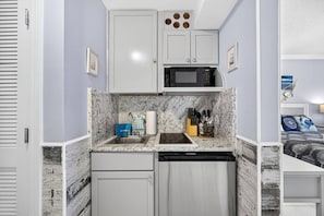 A compact kitchen with a built-in microwave, a sink, and a dishwasher. - Steps to the Sand! Gulf Front Studio at Boardwalk Resort – Pool, Hot Tubs, Tiki Bar & More! (Panama City Beach)