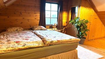 A cozy room with a bed, a window, and a potted plant.