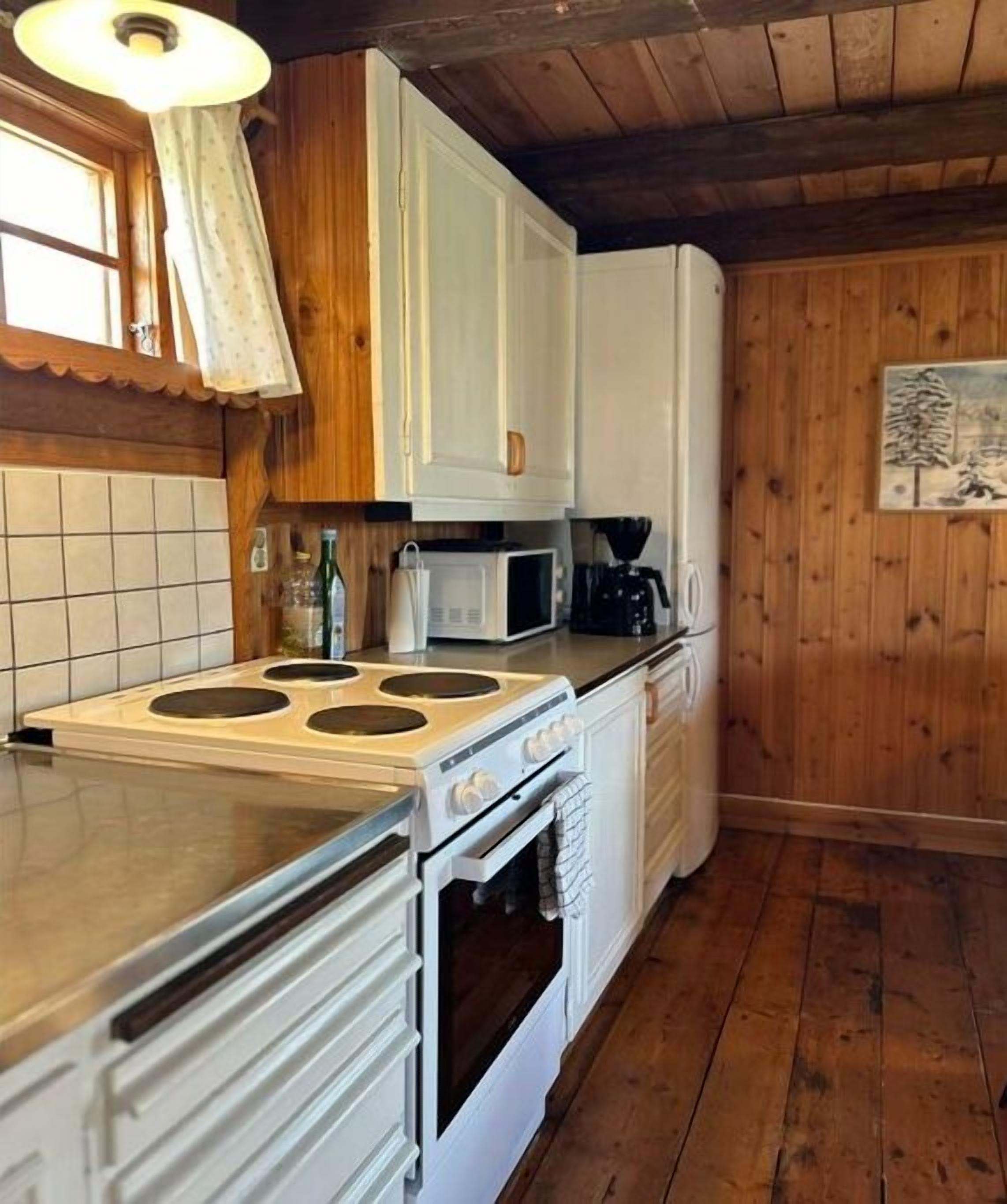 A kitchen with white cabinets, a stove, a microwave, and a refrigerator.