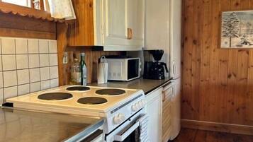 A kitchen with white cabinets, a stove, a microwave, and a refrigerator.
