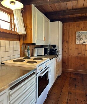 A kitchen with white cabinets, a stove, a microwave, and a refrigerator.