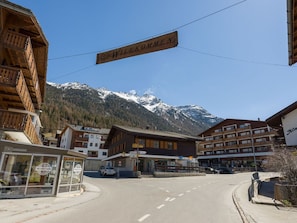 Einladendes Schild über einer Straße, im Hintergrund Gebäude und ein Berg.