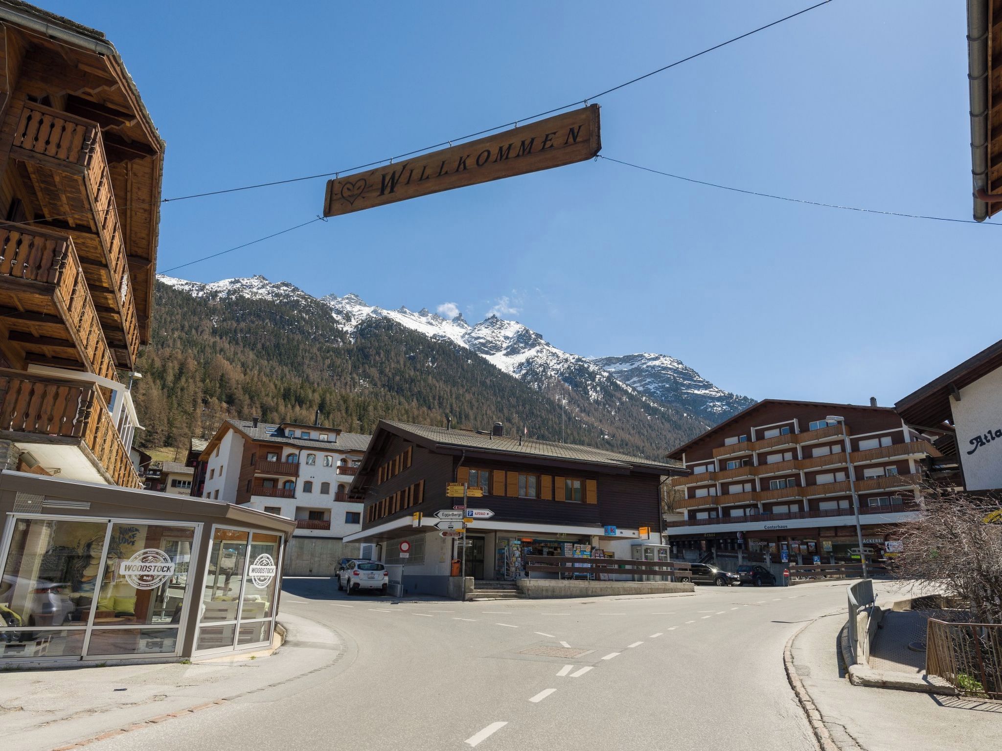 A street with a 'WILLKOMMEN' sign, buildings, and a mountain backdrop.