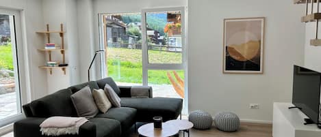A modern living room with a sectional sofa, a coffee table, and a TV stand.