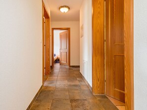 A hallway with wooden doors and a tiled floor. - Försterli West, (Grächen), 3002 by Interhome (Grächen)