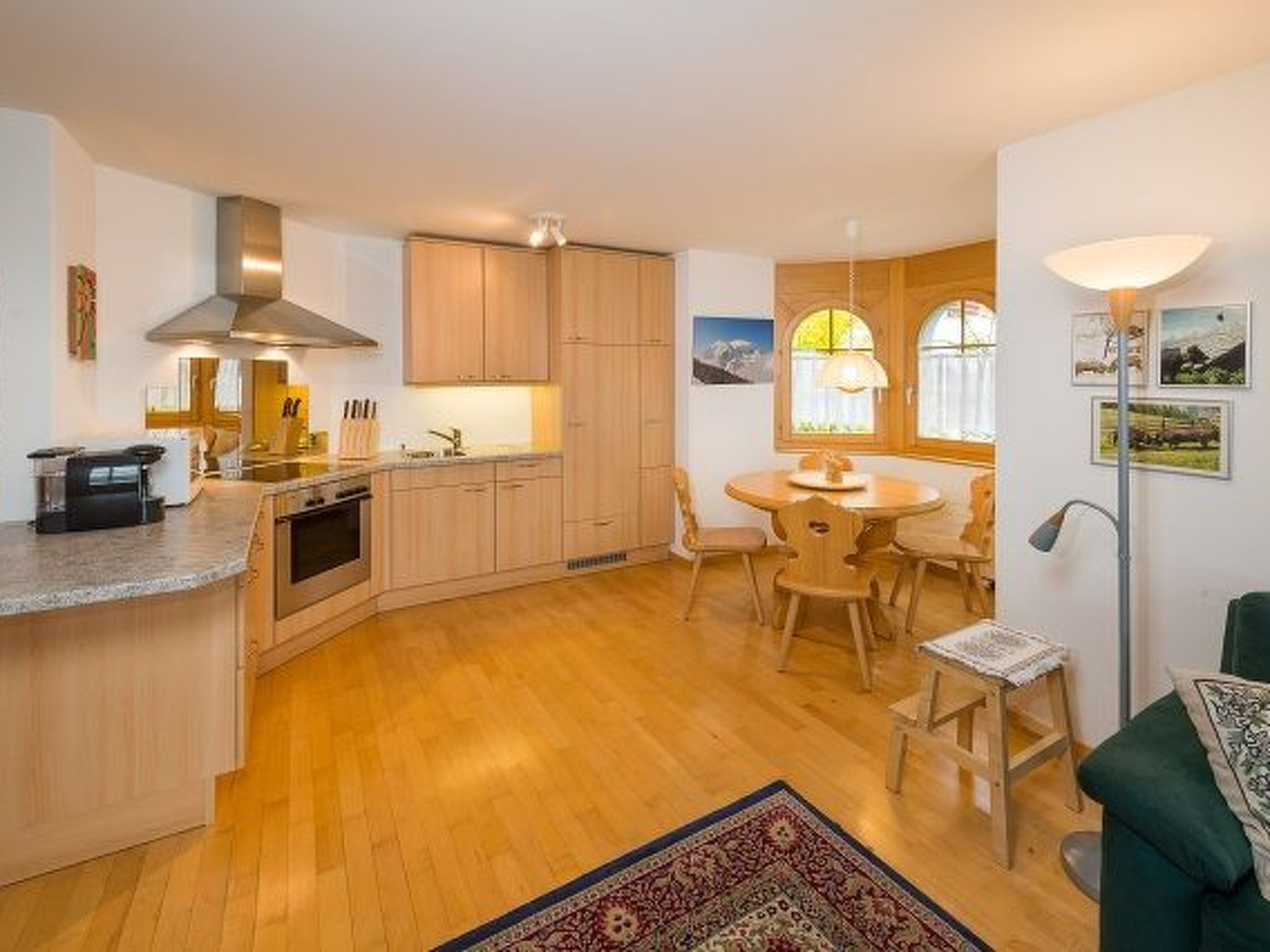 A compact kitchen with wooden cabinets, a central island, and a dining area with a round table and chairs.