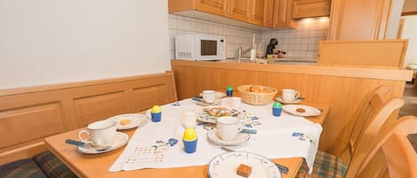 Ett mysigt kök med träskåp, en mikrovågsugn och ett matbord som är dukat för en måltid.