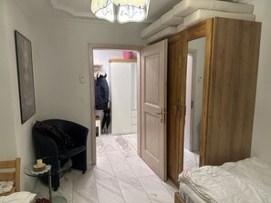 Ein Schlafzimmer mit einem Bett, einem Schrank, einem Stuhl und einem Tisch mit einer Kerze.
