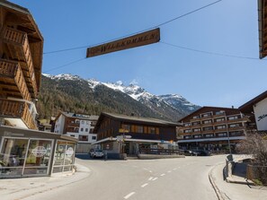 Einladendes Schild über einer Straße, im Hintergrund Gebäude und ein Berg.
