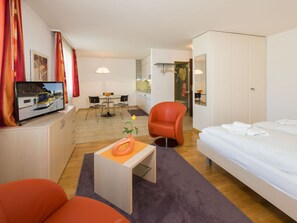 Habitació d'hotel amb un llit, una taula de treball, una cadira, televisió i zona de cuina.
