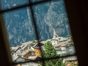 Ein Bergdorf mit traditioneller Architektur, darunter eine Kirche mit einem Kirchturm und Häuser mit geneigten Dächern.