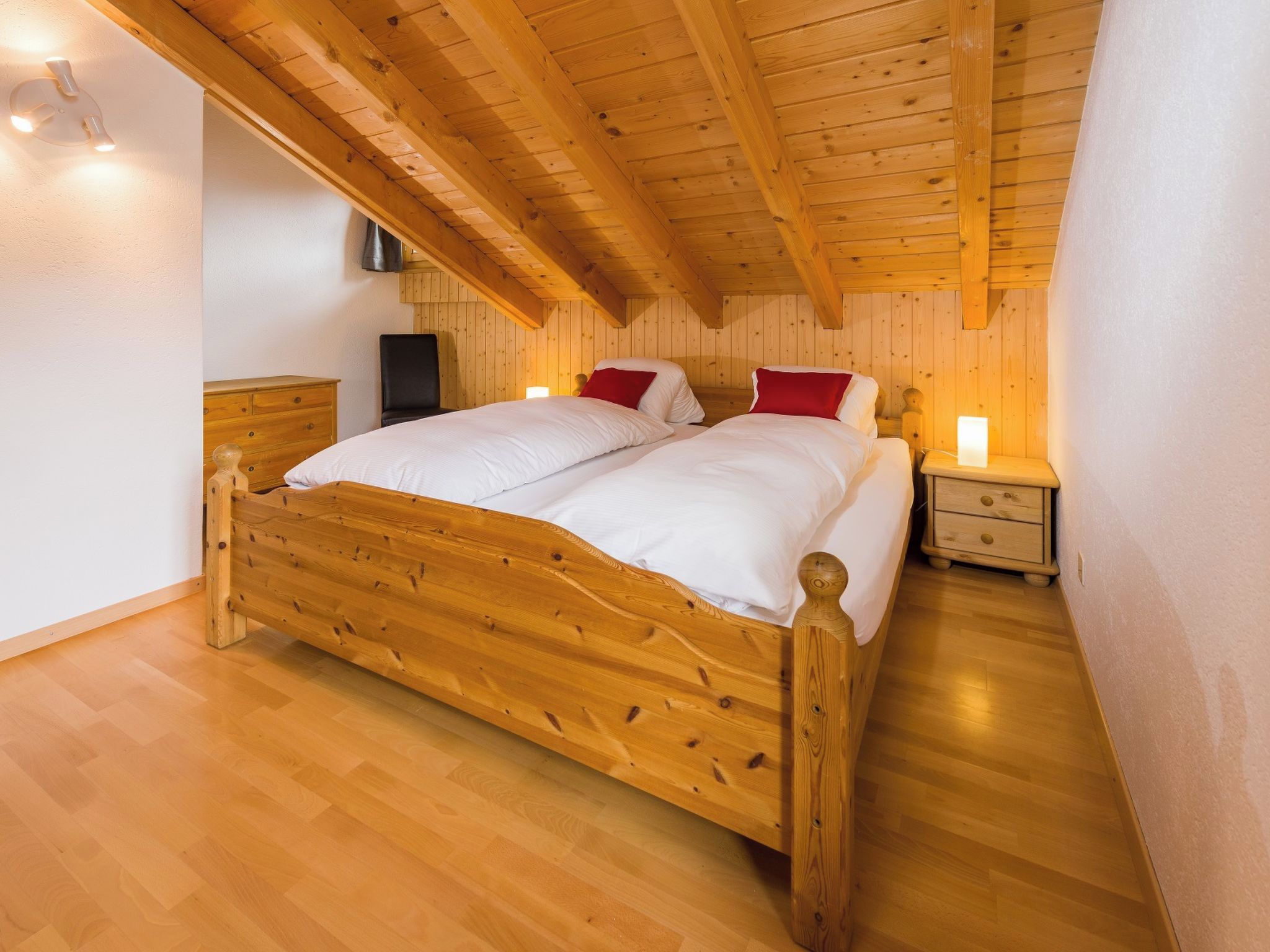 A wooden bed in a room with a sloped ceiling and wooden walls.