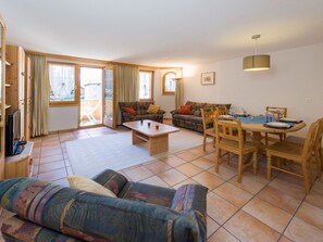 A spacious living room with a sofa, a coffee table, and a dining area with chairs and a table set for a meal. - Paradiso 2, (Grächen), 2003 by Interhome (Grächen)