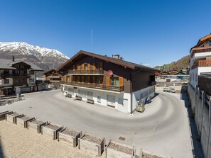 A hotel with a wooden facade, a balcony, and a mountain backdrop. - Ferienwohnungen Postgebäude, (Grächen), by Interhome (Grächen)