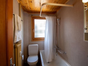 A compact bathroom with a toilet, bathtub, and shower. - Bergsonne, (Grächen), by Interhome (Grächen)