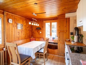 A wooden cabin interior with a dining table, chairs, a kitchen area, and a window. - Bergsonne, (Grächen), by Interhome (Grächen)