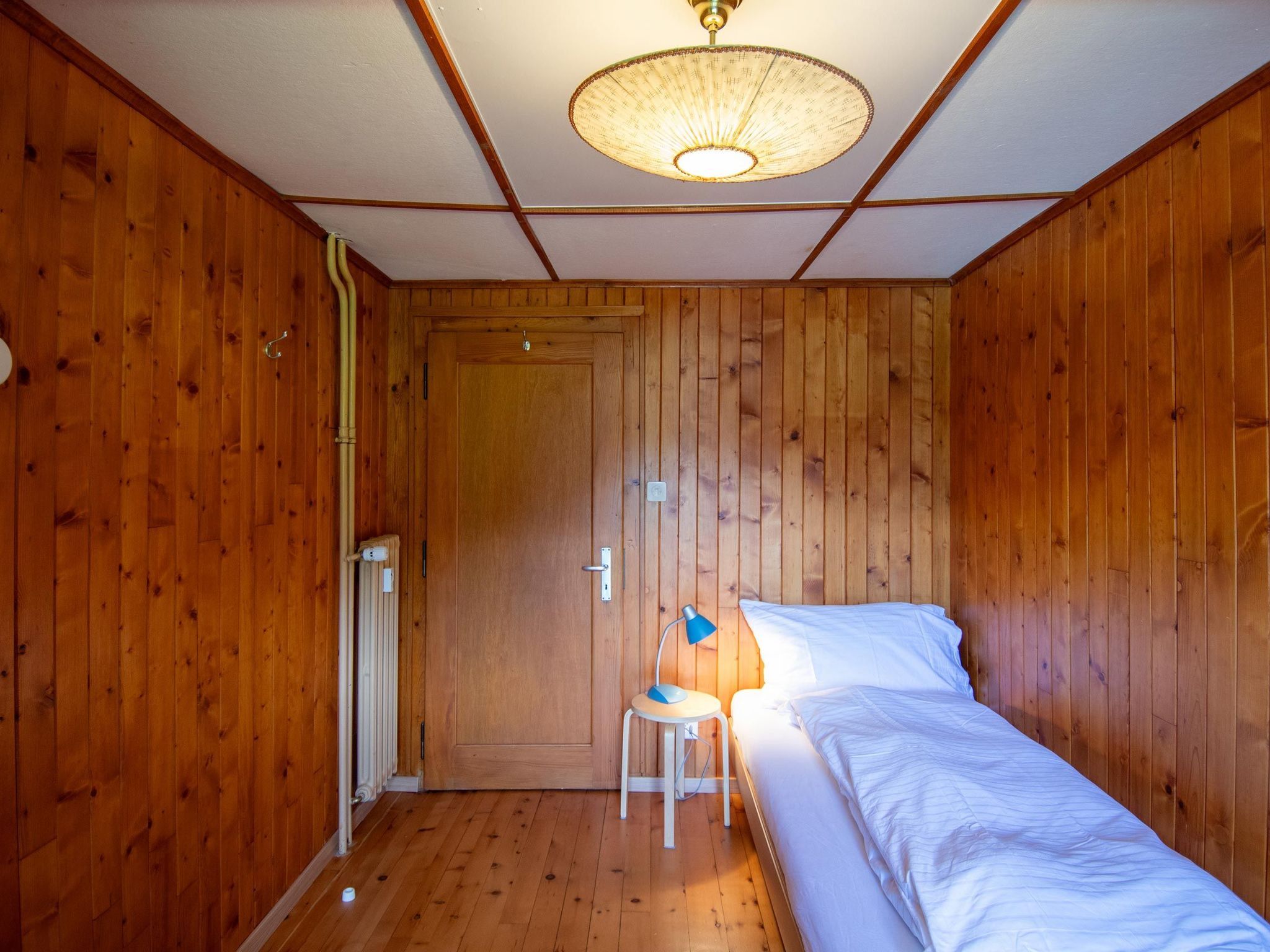 A small, cozy room with wooden walls and a single bed.