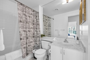 Une salle de bain moderne équipée de toilettes, d’un lavabo et d’un rideau de douche.
