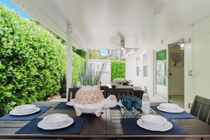 An outdoor patio with a table set for dining, surrounded by greenery. - Sea Turtle Sanctuary by the Beach! Heated Pool! (Juno Beach)