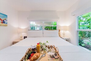 A hotel room with a large bed, a window with a view of greenery, and a breakfast tray on the bed. - Sea Turtle Sanctuary by the Beach! Heated Pool! (Juno Beach)