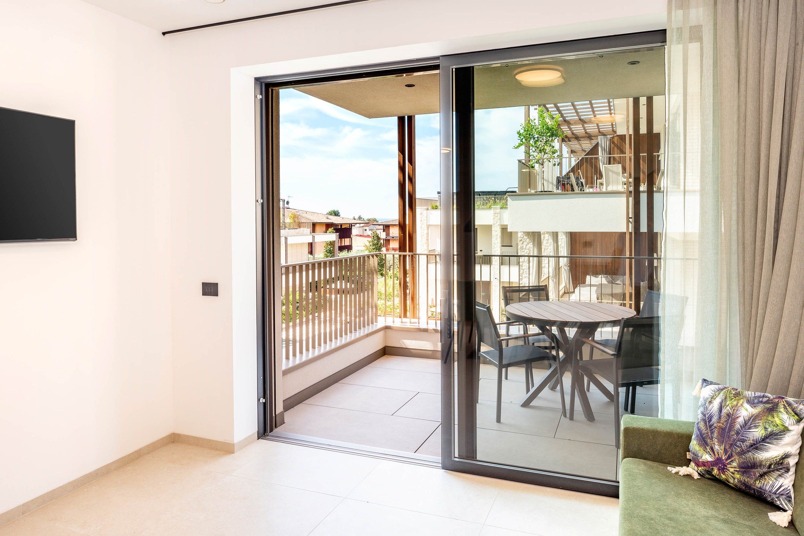 Un appartement moderne doté d’une porte-fenêtre coulissante donnant sur un balcon avec une table et des chaises.