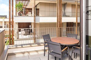 Ein Balkon mit Tisch und Stühlen, einem Holzzaun und Blick ins Innere des Gebäudes.