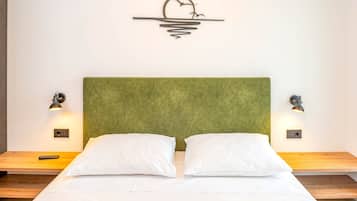 Una cama con cabecera verde, dos almohadas blancas y dos lámparas de pared a cada lado.
