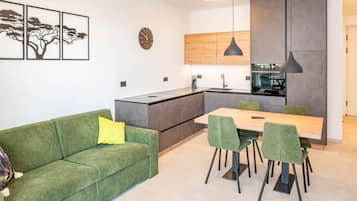 Una cocina moderna con comedor, sofá tapizado en verde y una obra de arte en la pared.