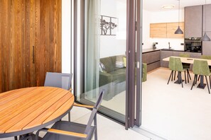 Ein modernes Interieur mit einem Holzes Esstisch, einer Couch und einer Küchenzeile.